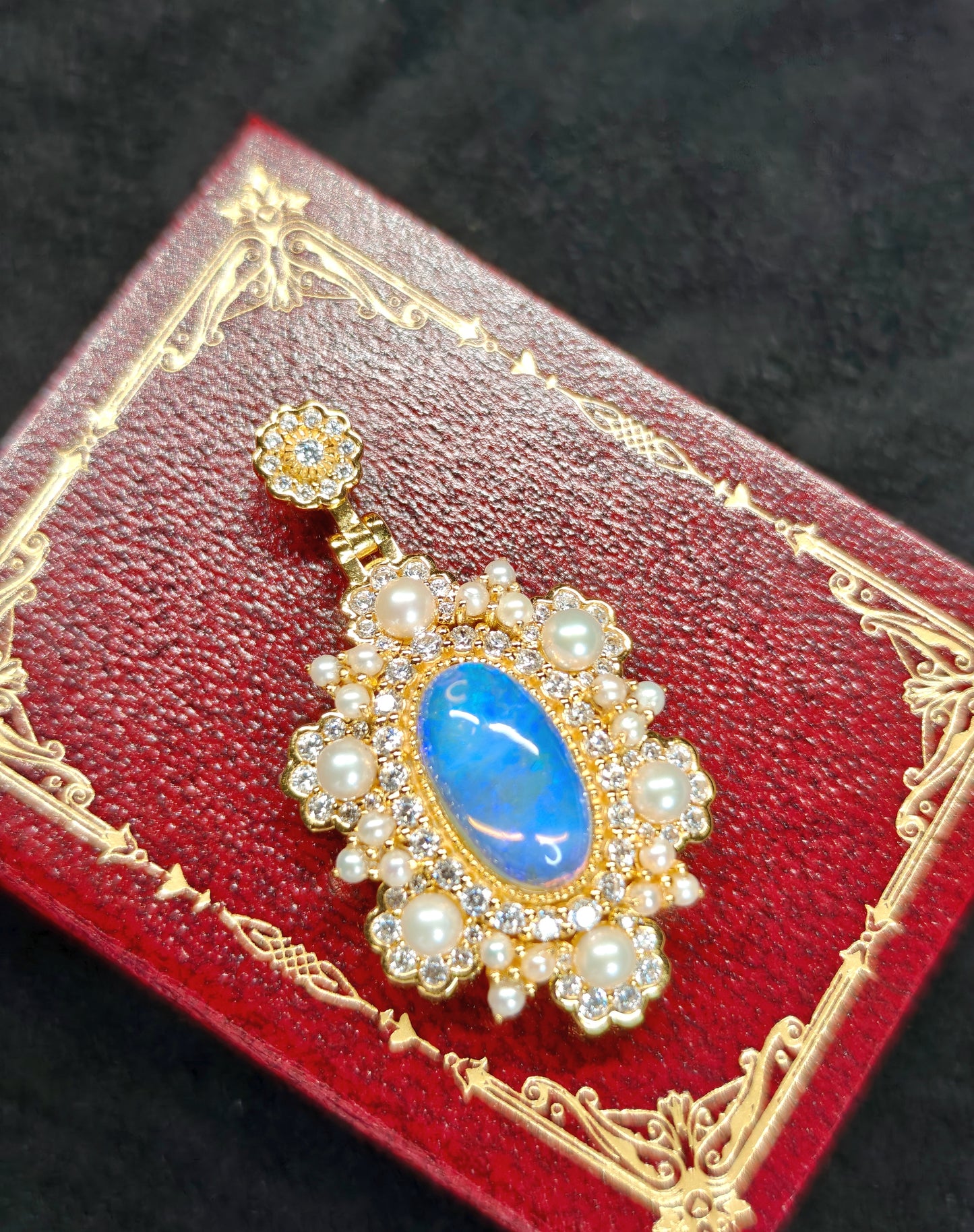 Vintage-style pendant featuring a large central blue crystal opal surrounded by pearls 