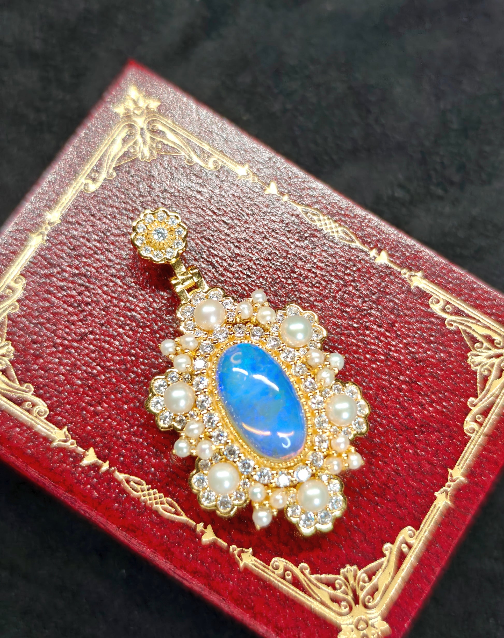 Vintage-style pendant featuring a large central blue crystal opal surrounded by pearls 