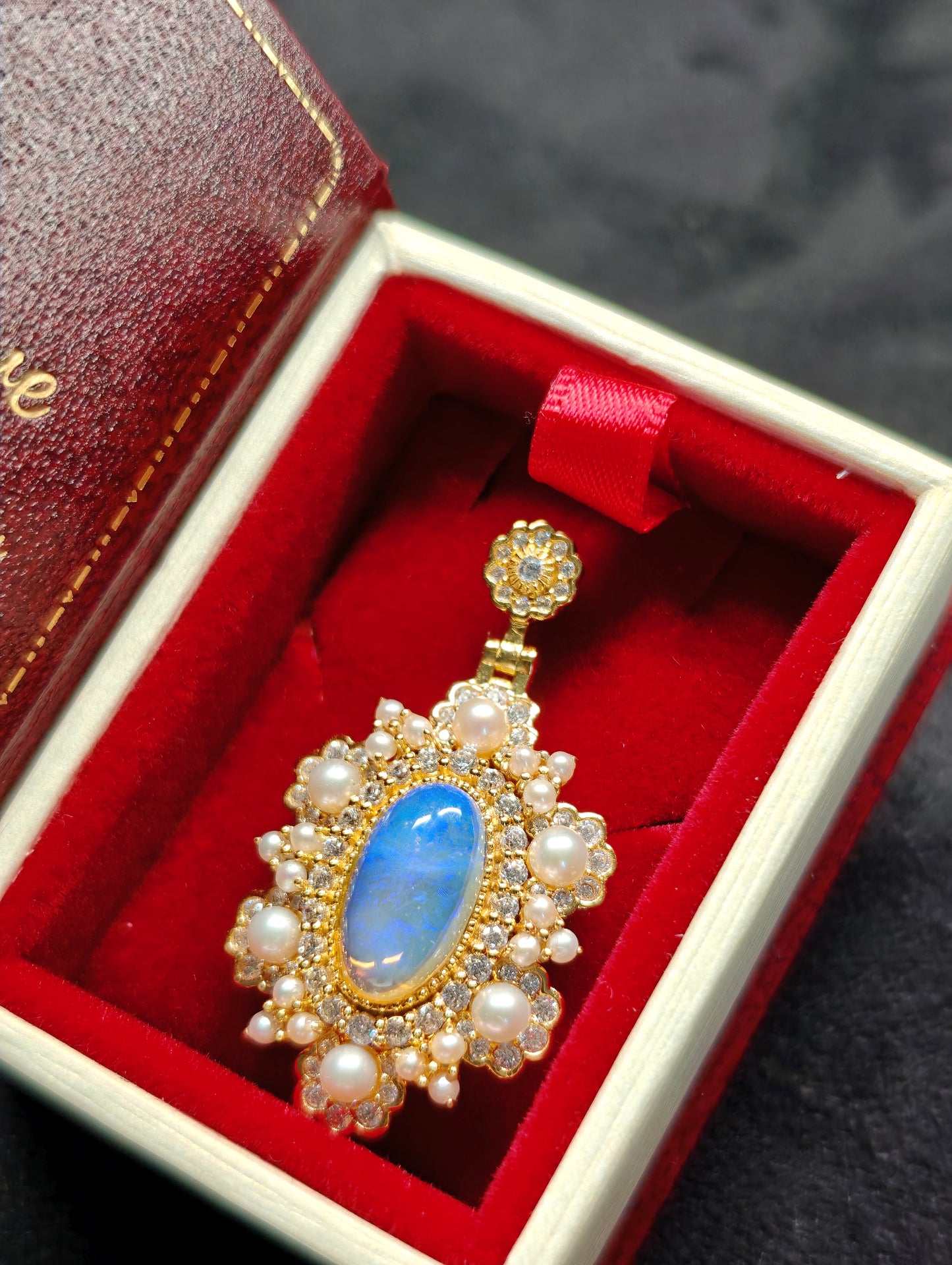Vintage-style pendant featuring a large central blue crystal opal surrounded by pearls 
